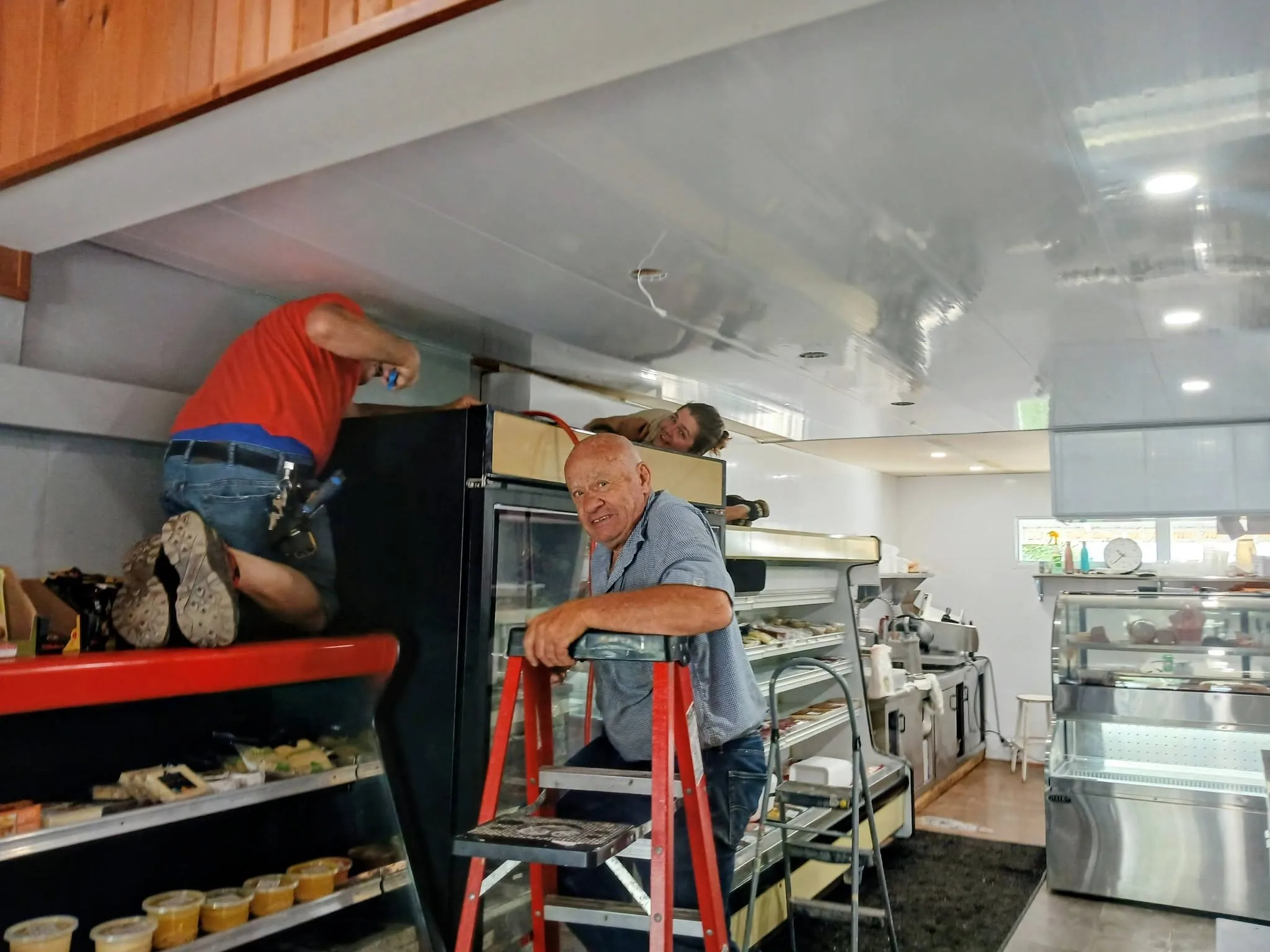 Le patriarche et l'équipe de la Boucherie Thibault en pleine rénovation du commerce, un escabeau au milieu du comptoir.